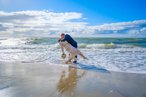 Newlywed couple kissing near waving sea — Stock Photo, Image