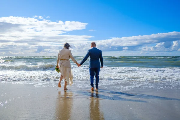 Noiva e noivo irreconhecíveis caminhando em direção ao mar — Fotografia de Stock