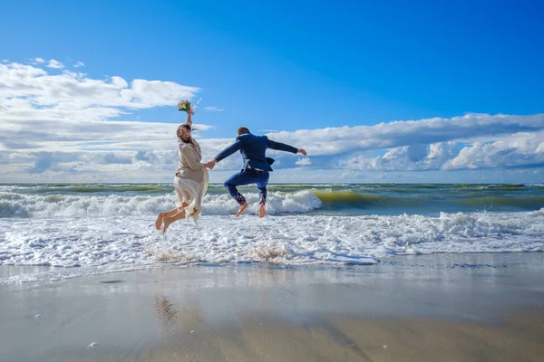 Šťastný novomanželský pár skákání u moře — Stock fotografie