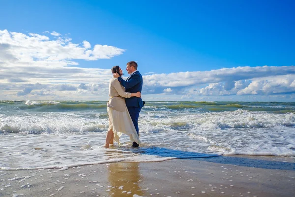 Casal recém-casado de pé em ondas do mar — Fotografia de Stock