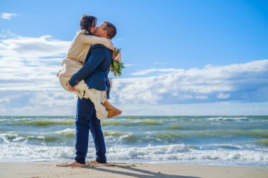 Mutlu gelin ve damat sahilde sarılıyor.