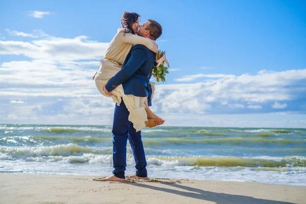 Glad brud och brudgum kramas på stranden — Stockfoto