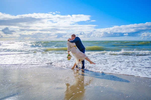 Casal recém-casado beijando perto do mar ondulando — Fotografia de Stock