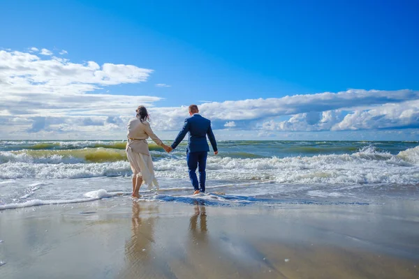Noiva e noivo irreconhecíveis caminhando em direção ao mar — Fotografia de Stock