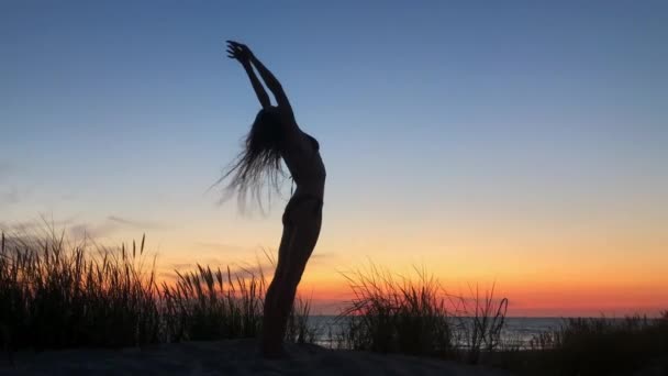 Anonieme vrouw doet yoga in de buurt van zee tijdens zonsondergang — Stockvideo