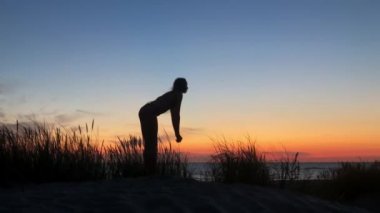 Esnek, anonim kadın gün batımında yoga yapıyor.