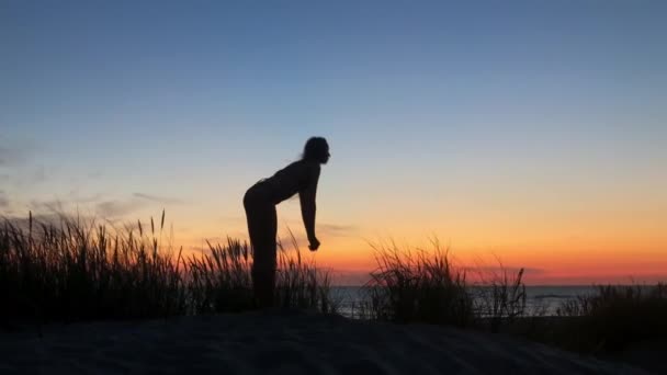 Ευέλικτη ανώνυμη γυναίκα κάνει γιόγκα το ηλιοβασίλεμα — Αρχείο Βίντεο