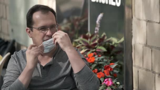 Férfi felvesz védő maszk teraszán kávézó — Stock videók