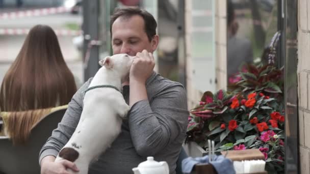 Щасливий зрілий чоловік дає ласощі собаці в кафе — стокове відео