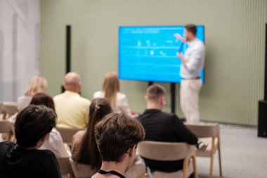 Modern iş seminerine katılan seyirciler, konuşmacı ekranda bir sunum yapacak.