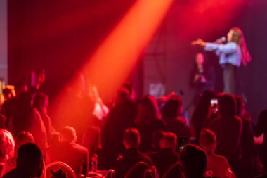 Seyirci sahnede canlı performansı seviyor. Çarpıcı kırmızı ışık dinamik atmosfer yaratıyor.