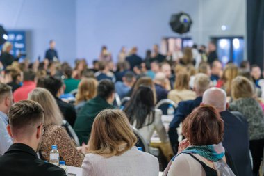 Konferans salonunda büyük bir dinleyici kitlesi oturuyordu. Profesyonel ve öğretici atmosfer.