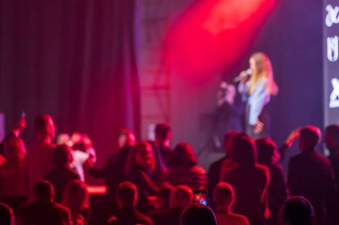 Seyirci sahnede canlı performansı seviyor. Çarpıcı kırmızı ışık dinamik atmosfer yaratıyor.