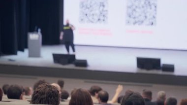 Resmi konferans sırasında sunucuyla birlikte sahnede konuşma yapmaya odaklanmış görünüm.