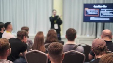 Katılımcıların sahnede slaytlarla sunum yapan konuşmacıları dinlediği profesyonel seminer..