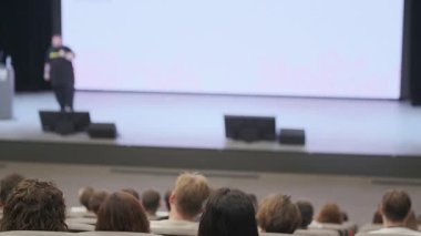 Seyirciler oturdular ve profesyonel bir seminer sırasında sahnede bir konuşmacıyı dinlediler..