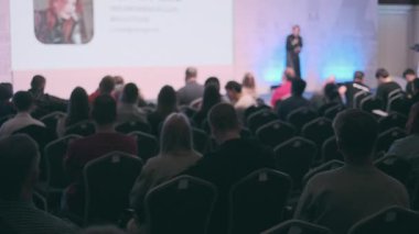 Konferans salonundaki profesyonel konferansta konuşmacıyı dinleyen katılımcıların bulanık görüntüsü.