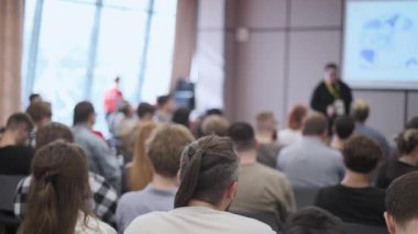 Oturan katılımcılarla yapılan konferans ayarları, profesyonel konular hakkında bir konuşmacı sunumuna bağlanıyor.