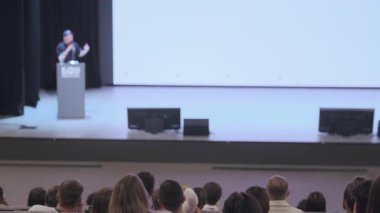 Seyirci geniş oditoryumda dikkatle dinlerken insan sahnede bir ders veriyor..