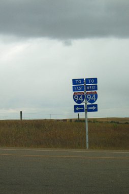 I94 - Montana Interstate highway 94 bulutlu bir günde yol işaretleri.
