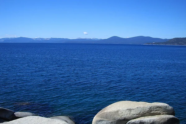 遠くの松の木 岩の海岸線とタホ湖の明るい青い海 — ストック写真