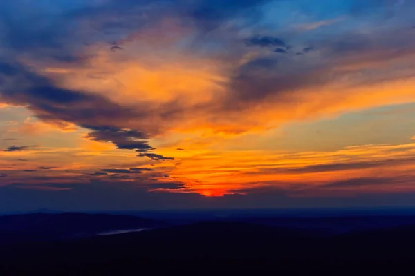 Sunset in the clouds above the distant hills — Stock Photo, Image