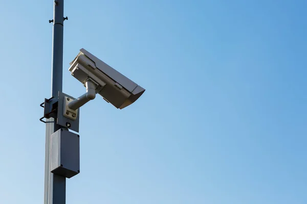 Outdoor Security camera on blue sky background. Mounted on a pole. Security view post