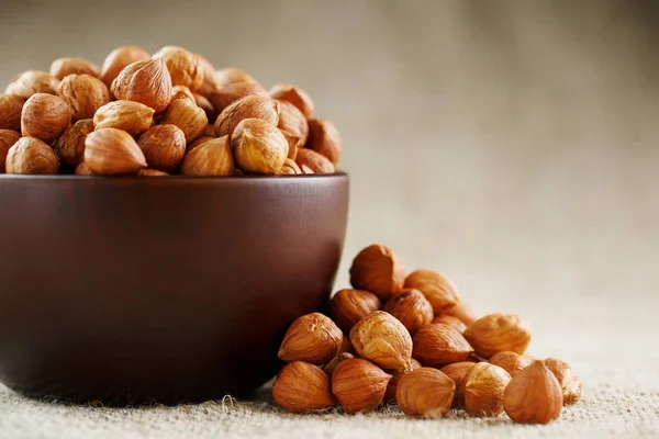 Peeled hazelnuts in a wooden, dark brown cup on a burlap cloth. Super Food, Raw. View from above.