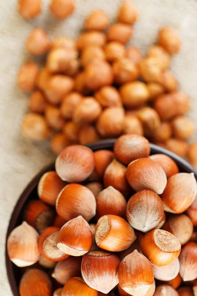 Peeled hazelnuts in a wooden, dark brown cup on a burlap cloth. Super Food, Raw. View from above.