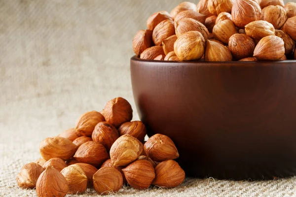 Peeled hazelnuts in a wooden, dark brown cup on a burlap cloth. Super Food, Raw. View from above.