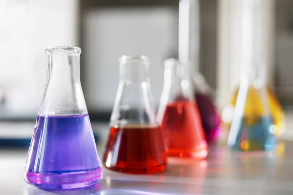 Chemical laboratory flask with blue purple-pink liquid stand on the table