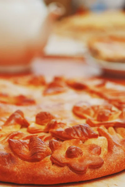 Russian pie with potatoes and mushrooms on the table. Freshly baked big cake decorated with flowers of their dough