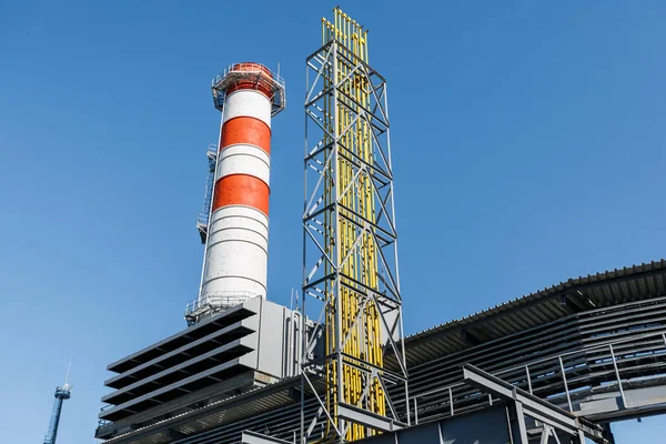 Gas turbine power plant on natural gas with chimneys of red-white color against a blue sky on a sunny day