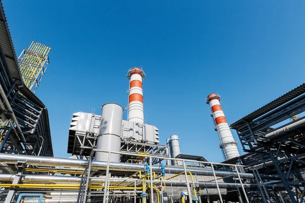 Gas turbine power plant on natural gas with chimneys of red-white color against a blue sky on a sunny day