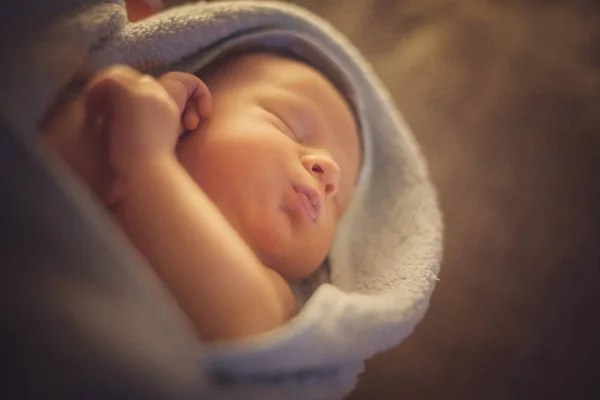 Newborn baby wrapped in a blanket folded handles, sleeping, close-up