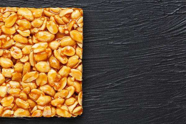 Golden boletus kozinaki from roasted peanut beans energy bars. Black textural background, top view