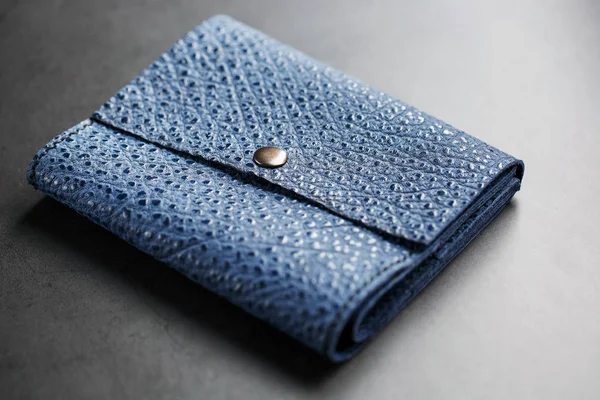 Dark blue leather wallet on a dark background top view. Close-up, purse details, rivet and firmware
