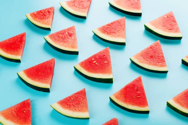 Pattern of slices of fresh slices of red and yellow watermelon on a blue background. Top view