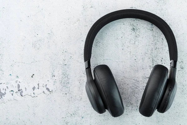 Wireless Black Headphones on a gray stone background. View from above. In-ear headphones for playing games and listening to music tracks