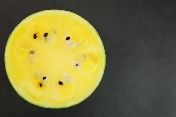 Half yellow watermelon on a black background, texture of juicy pulp of ripe yellow watermelon