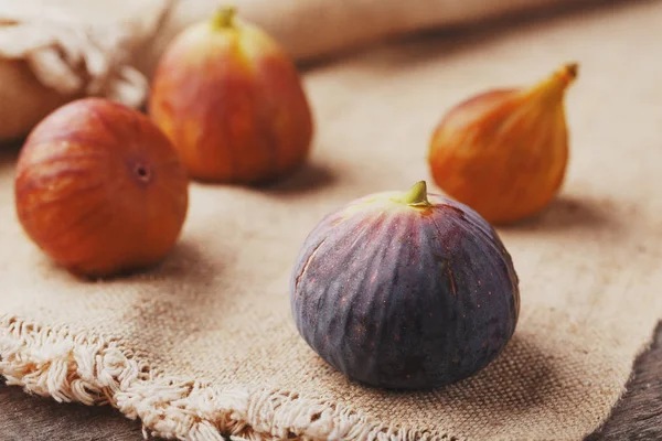 Figs on the table, group of fruits on a wooden farm table with burlap cloth. Slices of fig with pulp. Healthy and tasty fruit