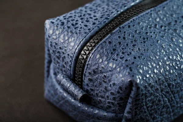 Bag for cosmetics and jewelry made of genuine dark blue leather, on a dark background. Handwork