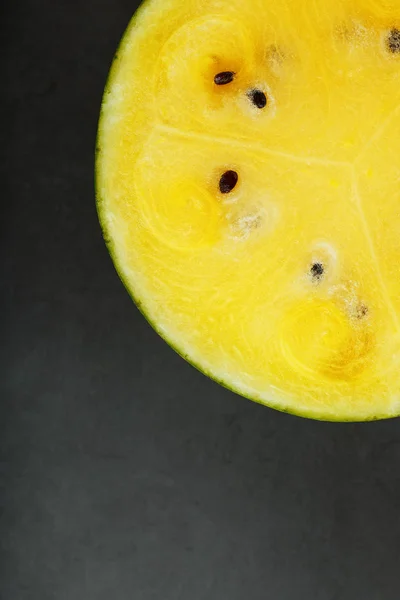 Half yellow watermelon on a black background, texture of juicy pulp of ripe yellow watermelon