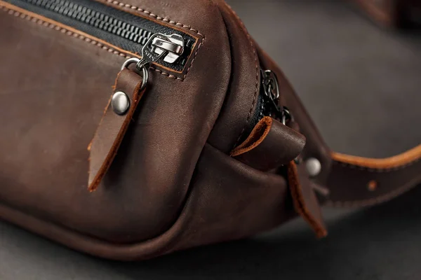 Handmade genuine brown leather on a dark background Brown belt bag. Elegant brown bag with a zipper