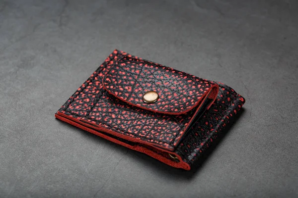 Red and black leather wallet on a black background. Handmade, wallet for money and credit cards.