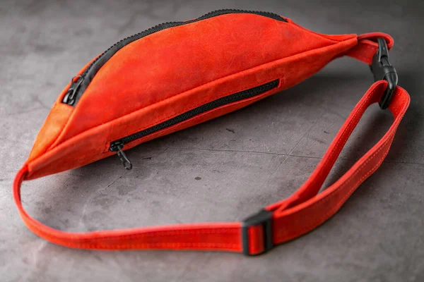 Red waist bag made of leather, banana on a gray background. Handmade