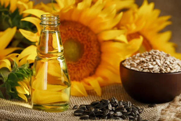 Sunflower oil with sunflower seeds and flowers on a wooden background. Composition in the village style. The concept of a bio-organic product.