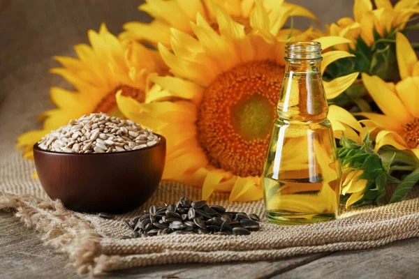 Sunflower oil with sunflower seeds and flowers on a wooden background. Composition in the village style. The concept of a bio-organic product.