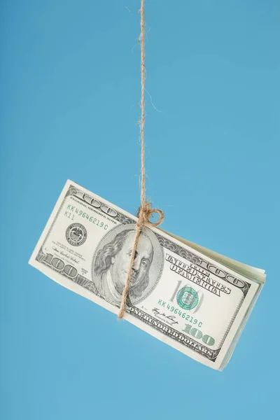 Dollars are tied on a rope, on a blue background. Isolate, free space. Concept of dirty money laundering. Hidden salaries, black payments, tax evasion, bribes, corruption.