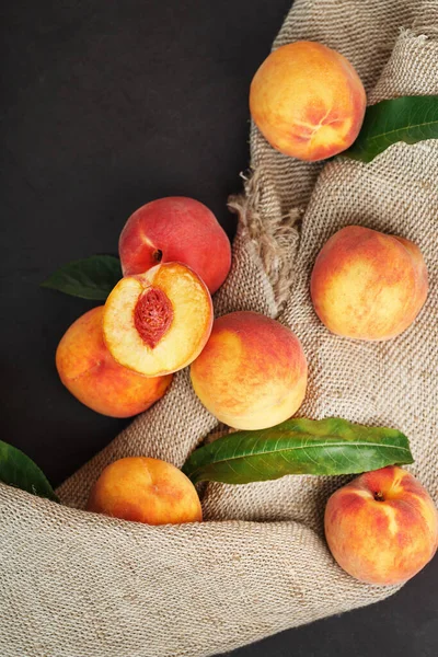 Sweet Peaches on a sharp stone table with a cloth of burlap and a slice of juicy peach with a bone. Top view, free space. Country style